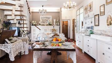A well-lit kitchen with a dining table set for a meal, surrounded by white cabinetry and a staircase.