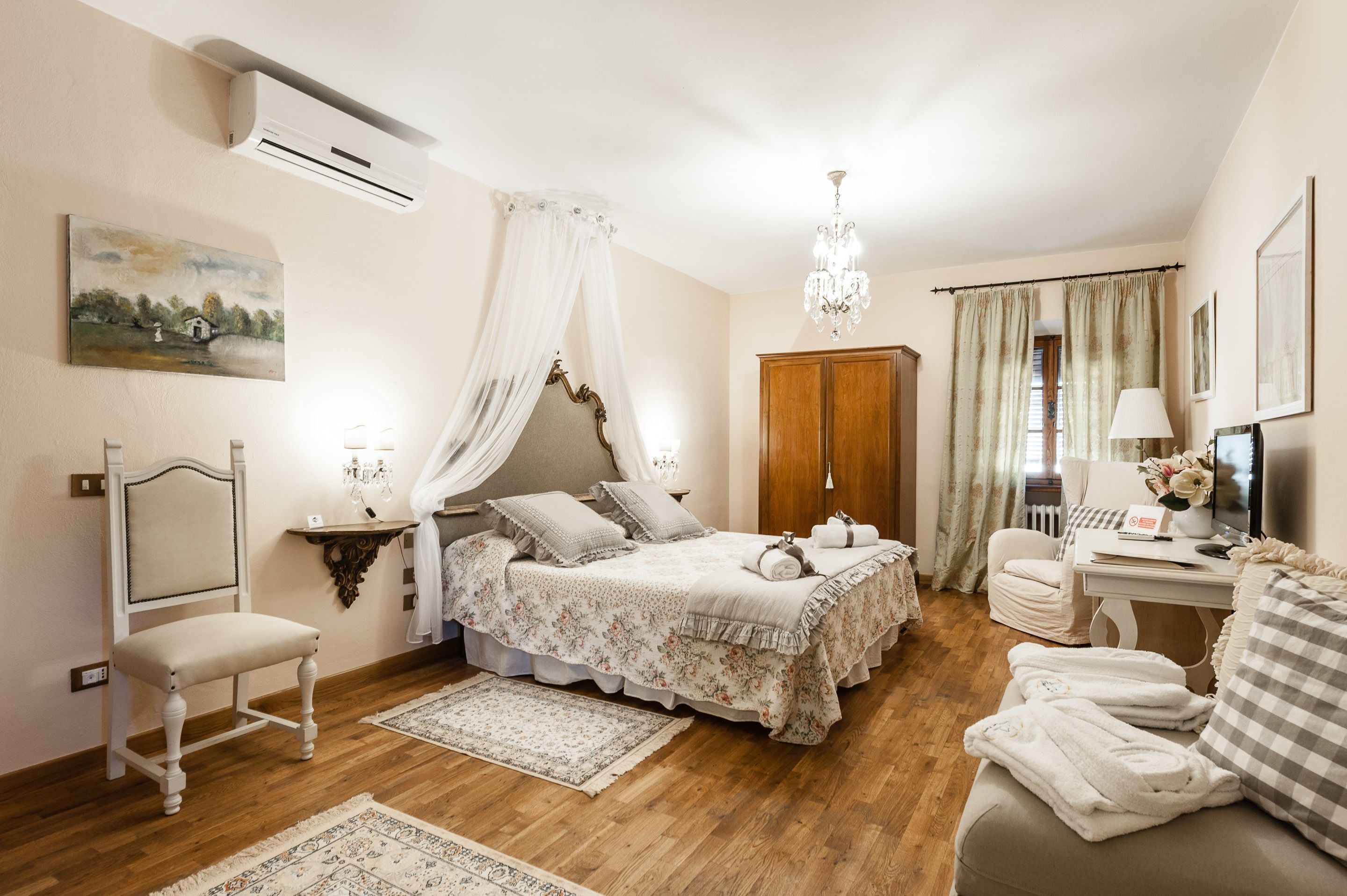 A bedroom with a bed, bedside table, chair, and a desk with a lamp.