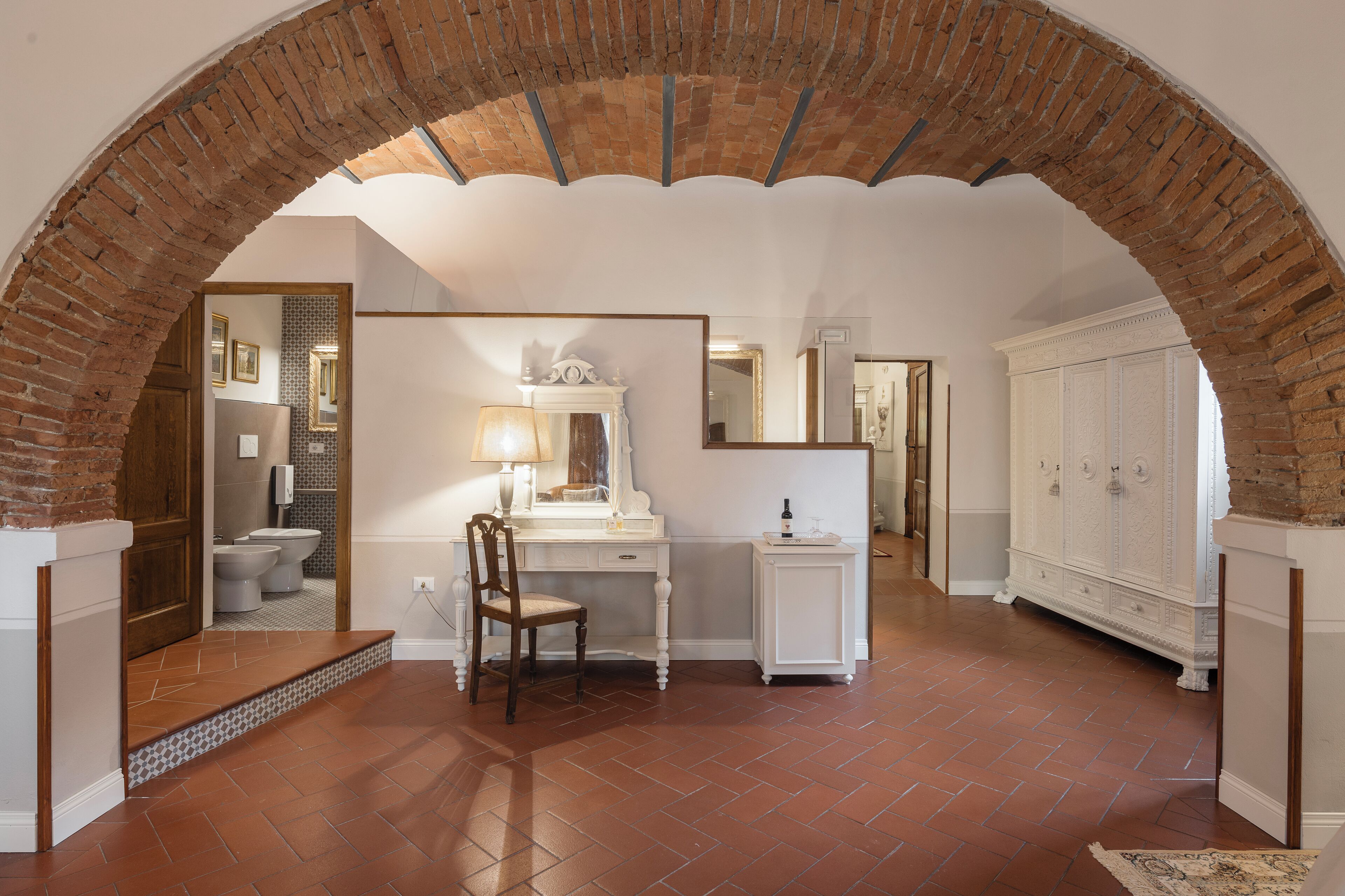 Une salle de bain avec un meuble-lavabo blanc, un miroir et une chaise en bois.