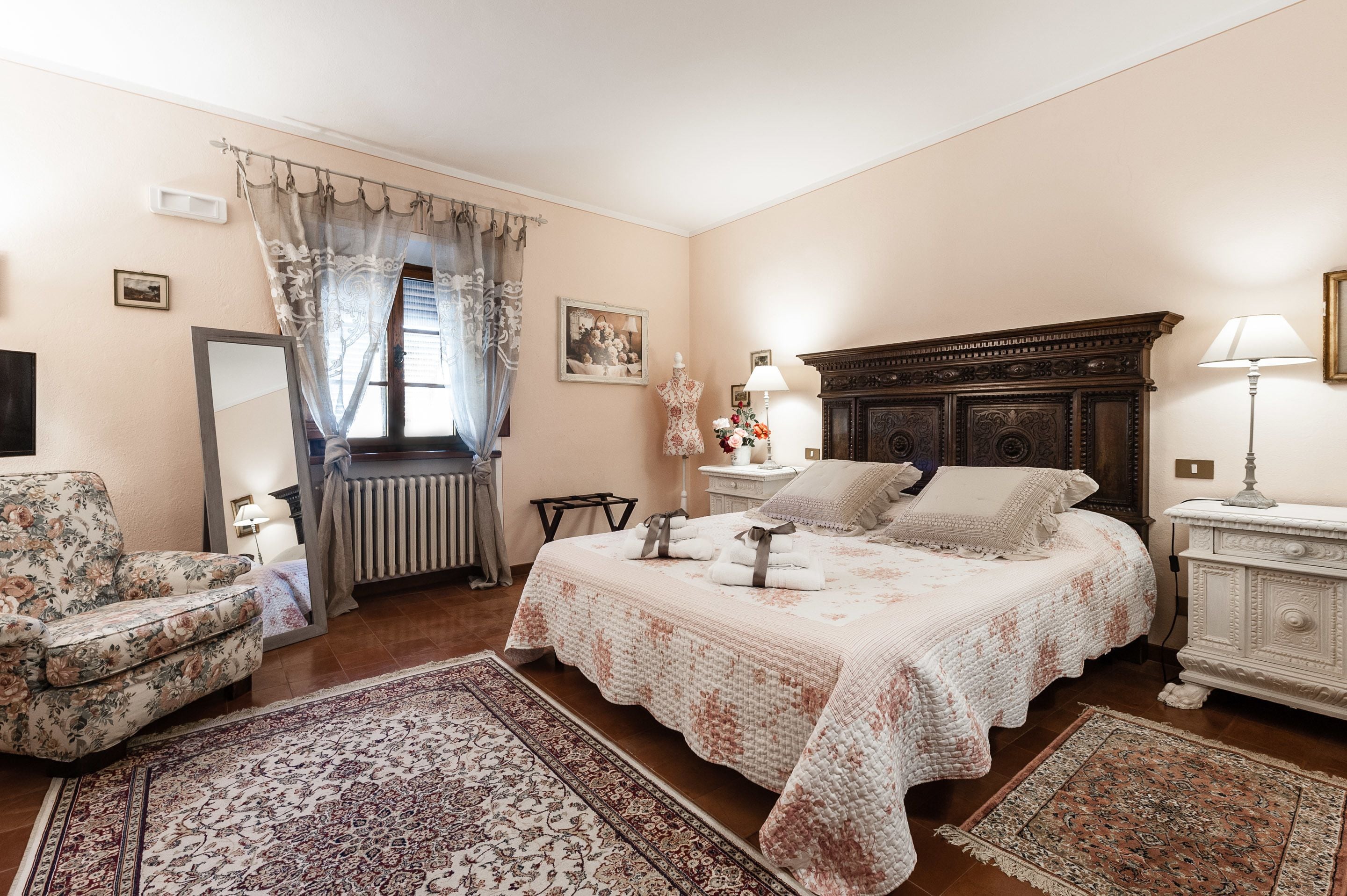 A bedroom with a large bed, a chair, a dresser, and a window with curtains.