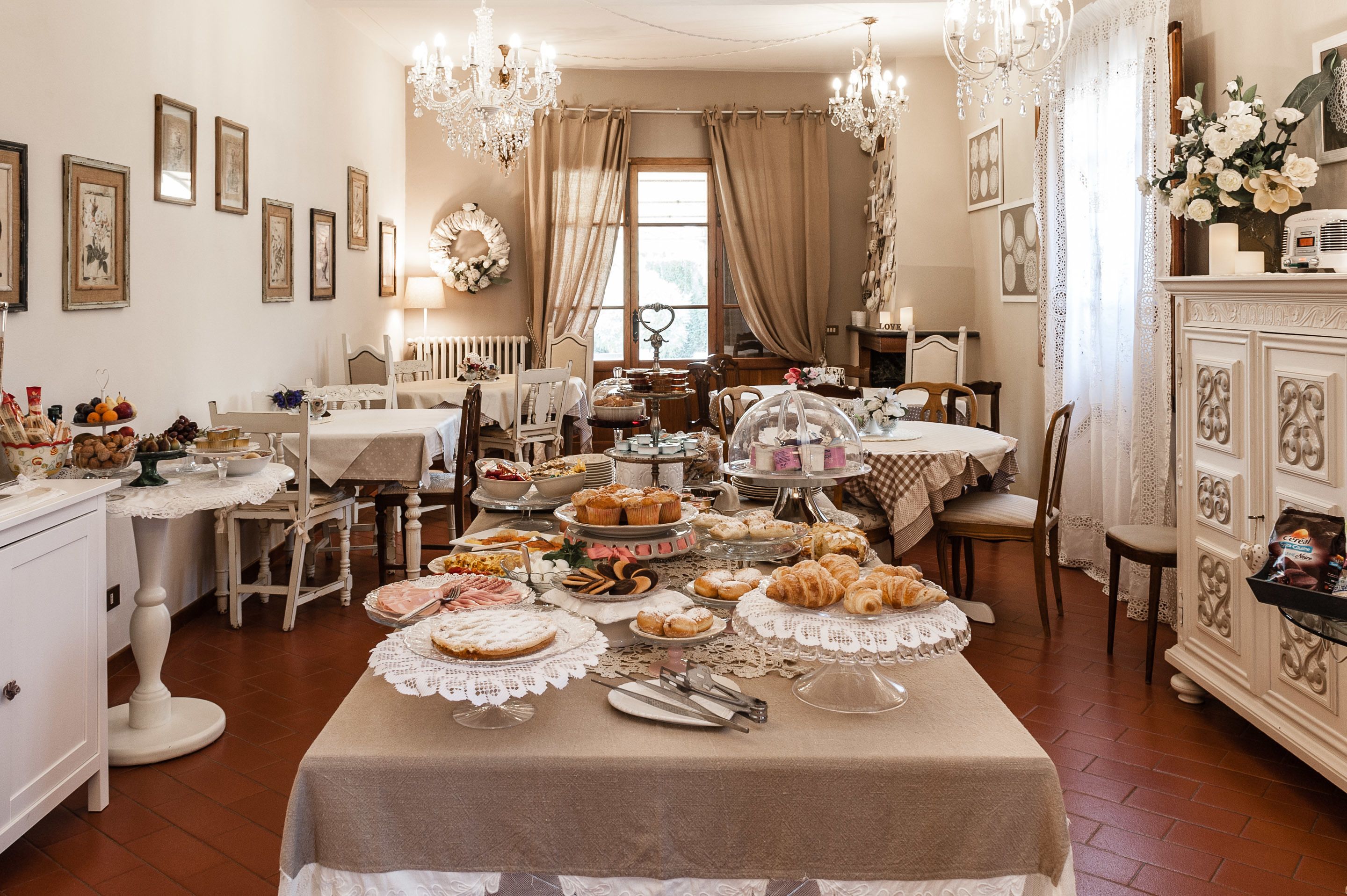 Comedor con varias mesas dispuestas para un bufé, que incluye una variedad de alimentos y una lámpara de araña.