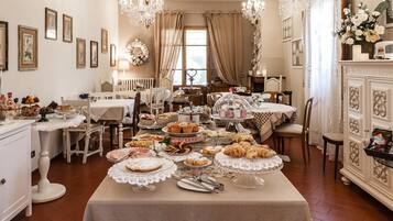 A dining area with multiple tables set for a buffet, featuring a variety of food items and a chandelier.