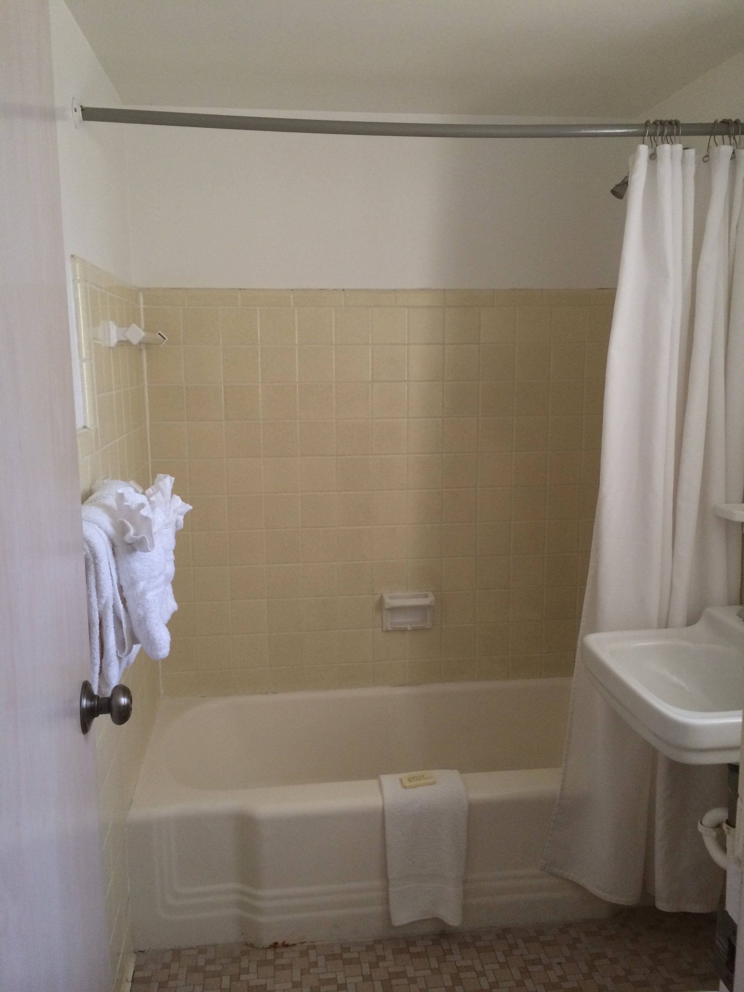 Un baño con bañera, cortina de ducha, lavamanos y perchero para toallas.