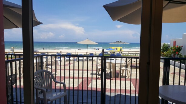 A balcony with a view of the beach, featuring outdoor seating and umbrellas. - Cove Motel Oceanfront (Daytona Beach)