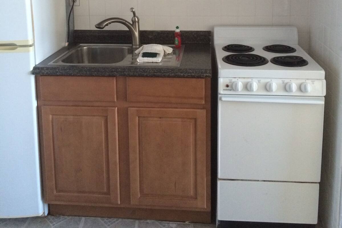 A kitchen with wooden cabinets, a white stove, and a sink.