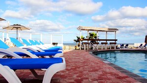 A poolside area with lounge chairs and a gazebo overlooking the ocean. - Cove Motel Oceanfront (Daytona Beach)