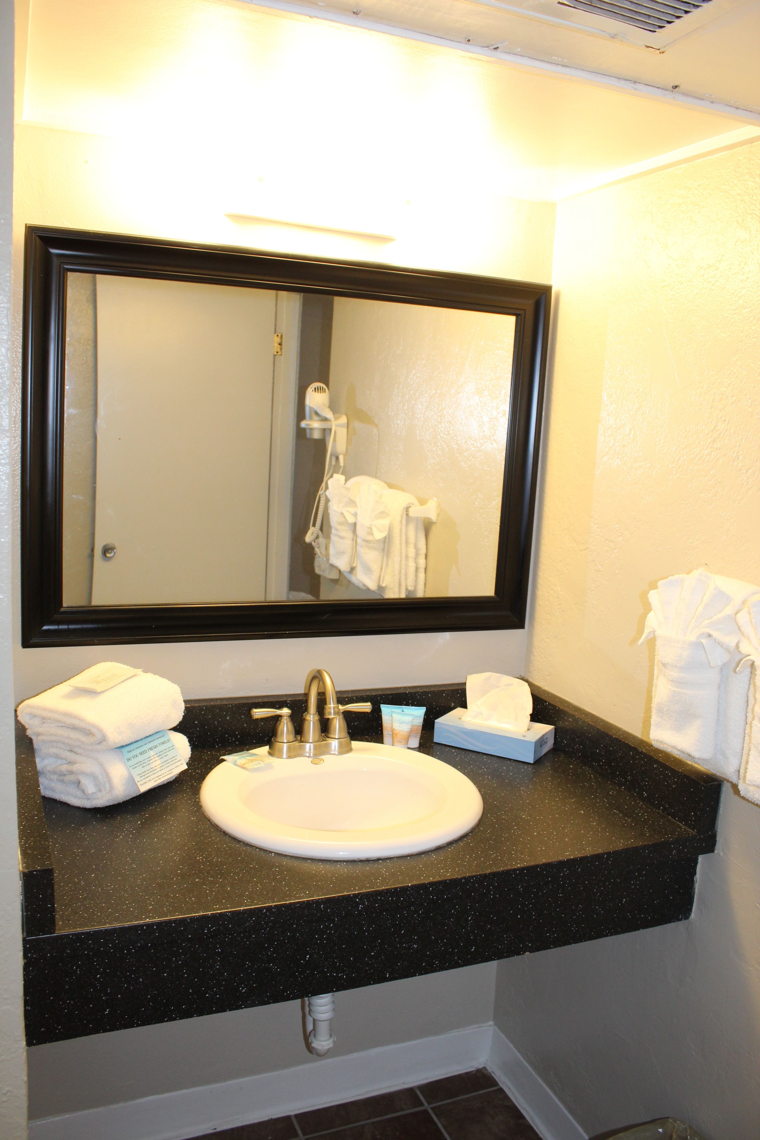 A bathroom with a sink, mirror, and towels.
