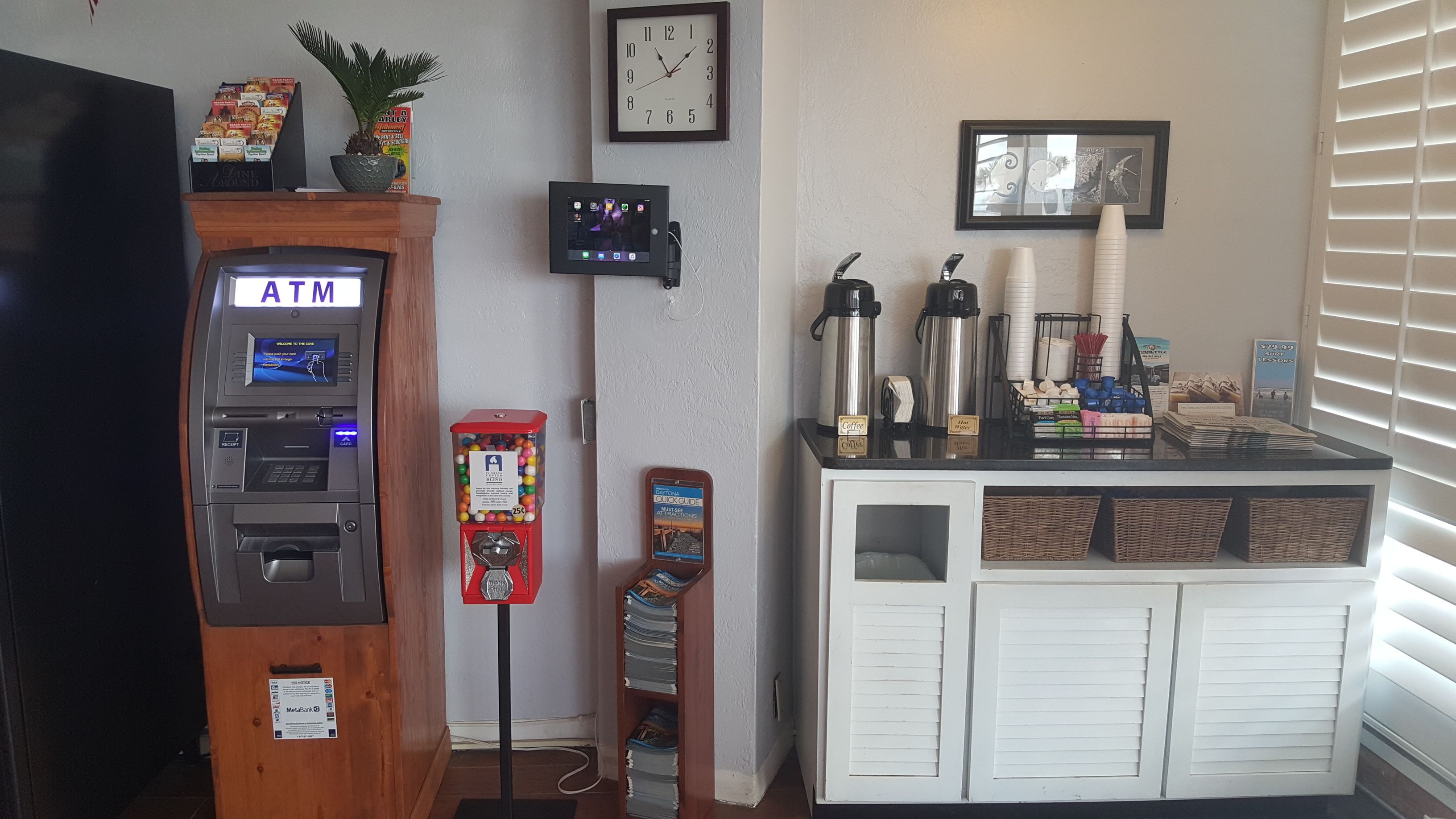 An ATM, a gumball machine, a coffee station, and a clock on the wall.