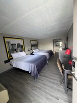 Habitación de hotel con dos camas, un escritorio y una lámpara roja.