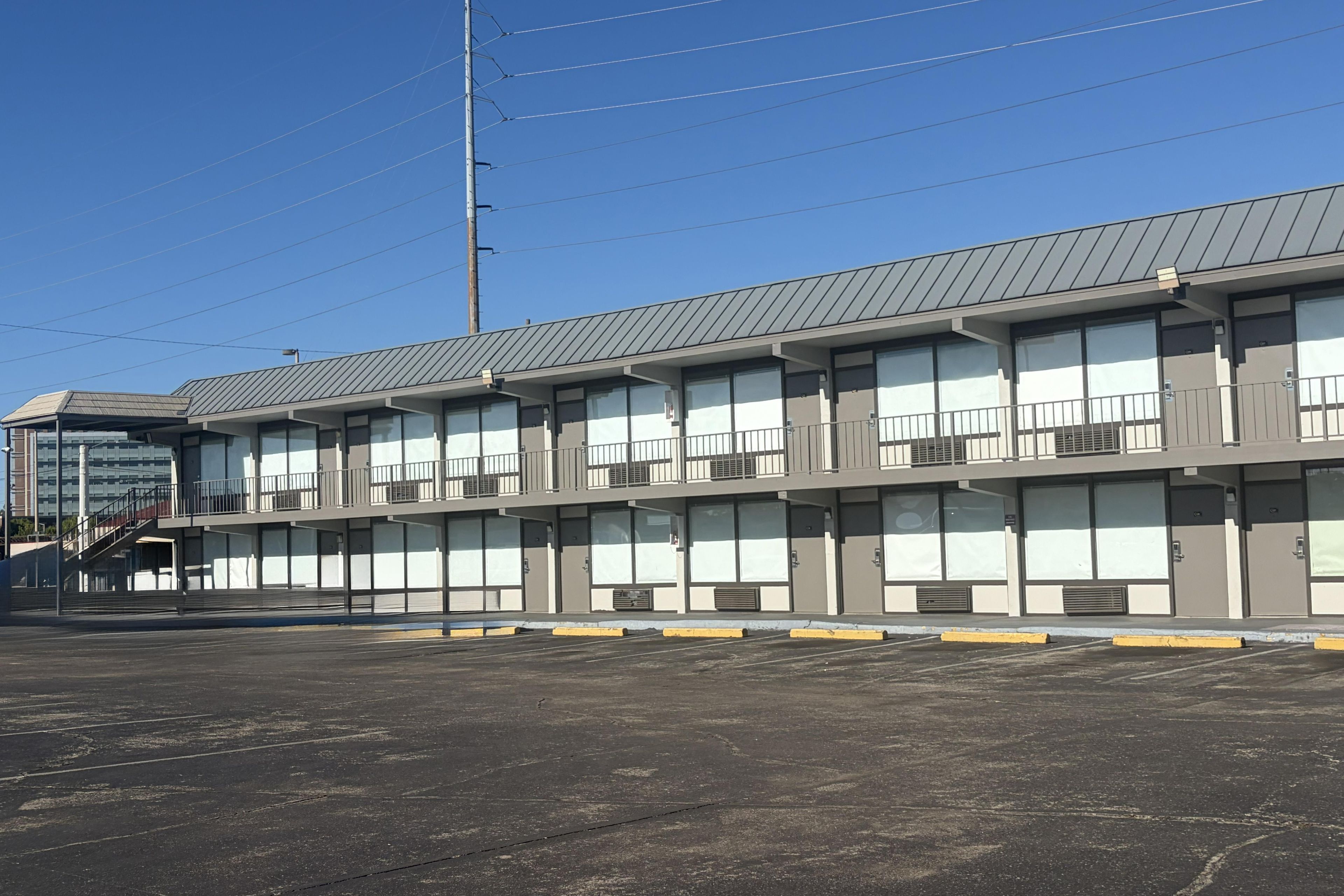 Un motel à plusieurs étages, doté d’un toit plat, de grandes fenêtres et d’un parking situé à l’avant.