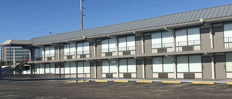 A multi-story motel with a flat roof, large windows, and a parking lot in front.