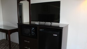 Una kitchenette compacta con microondas, refrigerador y televisor de pantalla plana sobre un mueble.