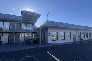 A modern building with a flat roof, large windows, and a covered outdoor area.