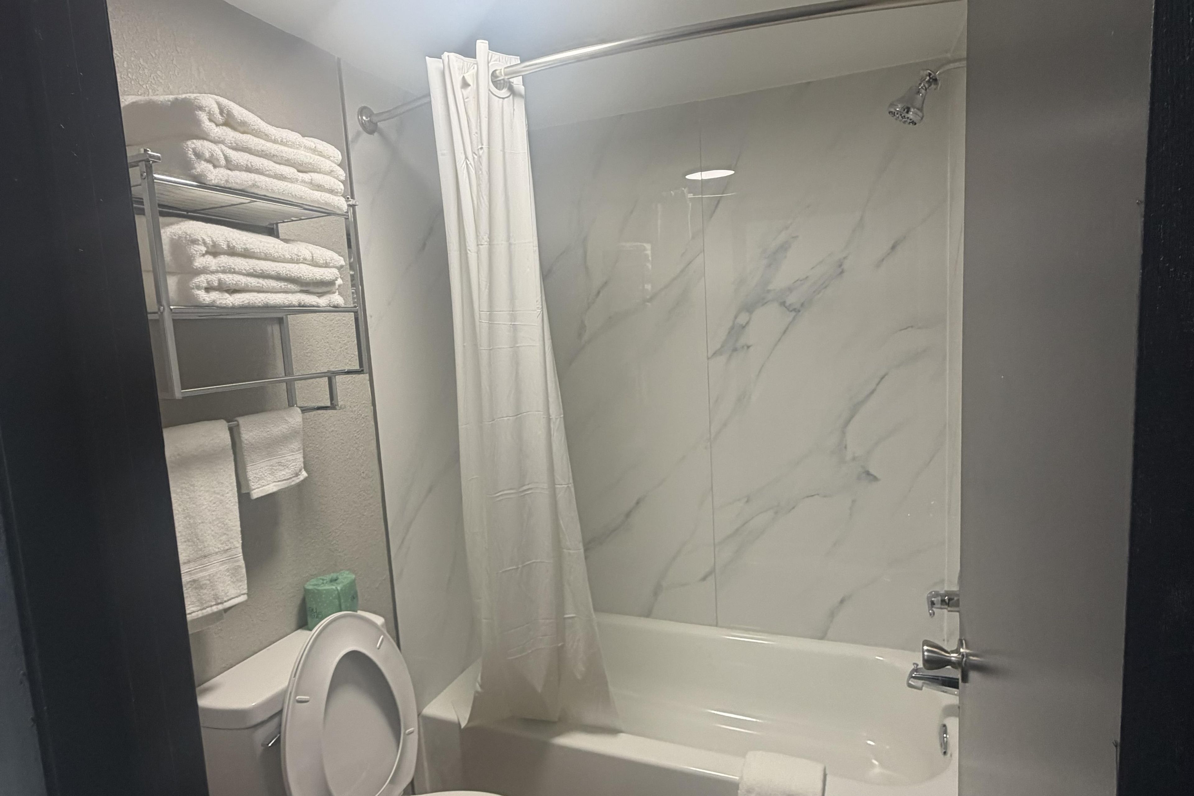 A bathroom with a toilet, a shower stall with a glass door, and a towel rack with folded towels.