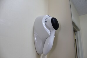 A white hair dryer mounted on a wall.