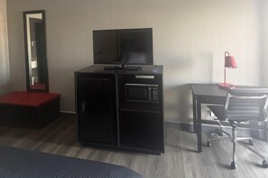 A hotel room with a bed, a desk with a chair, a television on a cabinet, and a red lamp. - Super 8 by Wyndham Birmingham (Birmingham)