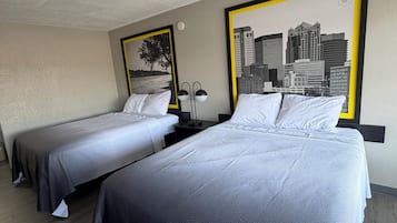 Habitación de hotel con dos camas, un cuadro de un paisaje urbano y una lámpara.