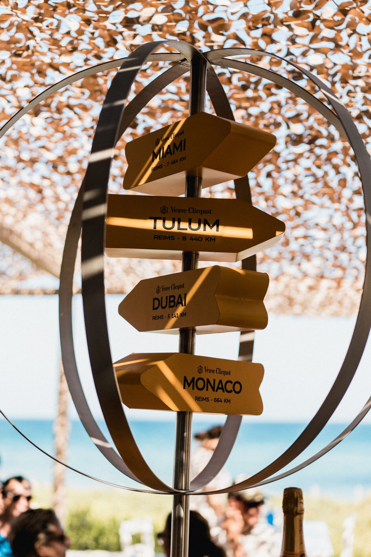 Um sinal de trânsito com setas indicando diferentes cidades: Miami, Tulum, Dubai e Mônaco.