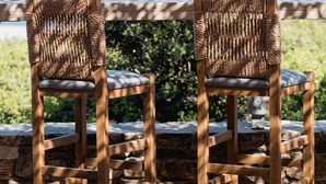Two wicker chairs with cushioned seats and backs, placed on a stone patio with a view of the ocean. - Soros Beach (Antiparos)