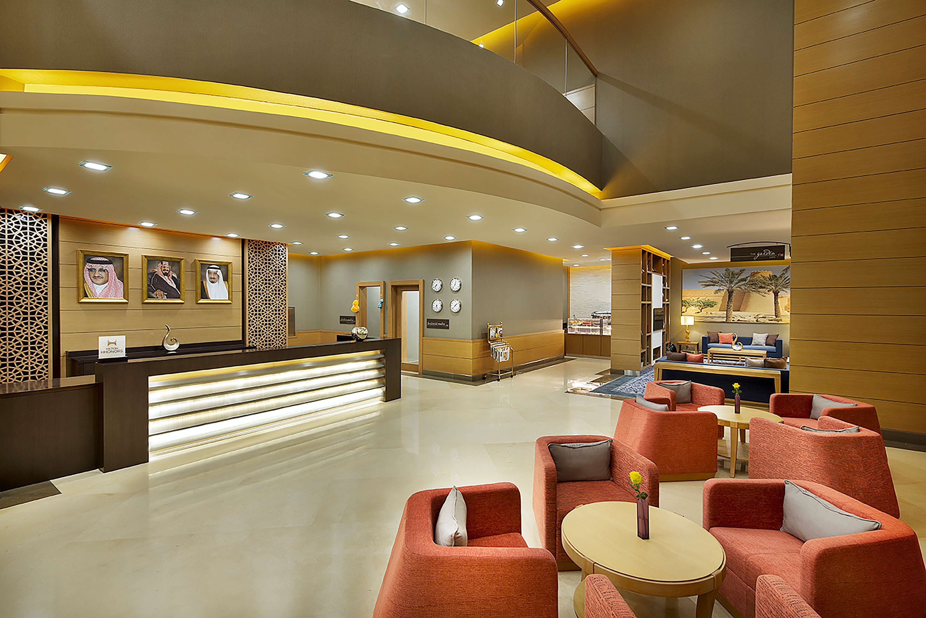 A hotel lobby with a reception desk, seating area, and a staircase.