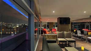 Un espace lounge moderne avec vue sur la ville, des sièges confortables et un bar.