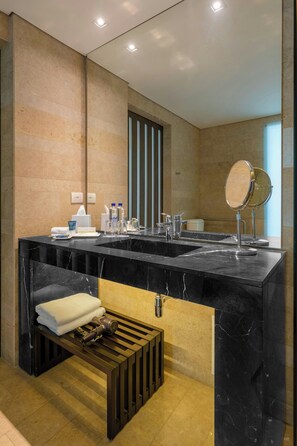 A modern bathroom with a black marble sink, a mirror, and a towel rack.