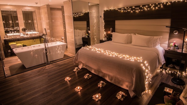 Une chambre à coucher moderne avec un grand lit, des tables de chevet, un miroir et une coiffeuse avec un lavabo.