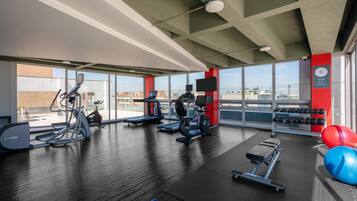 A gym with cardio machines, dumbbells, and exercise balls.