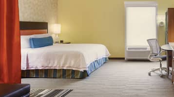Una habitación de hotel con cama, escritorio, silla, lámpara y ventana.