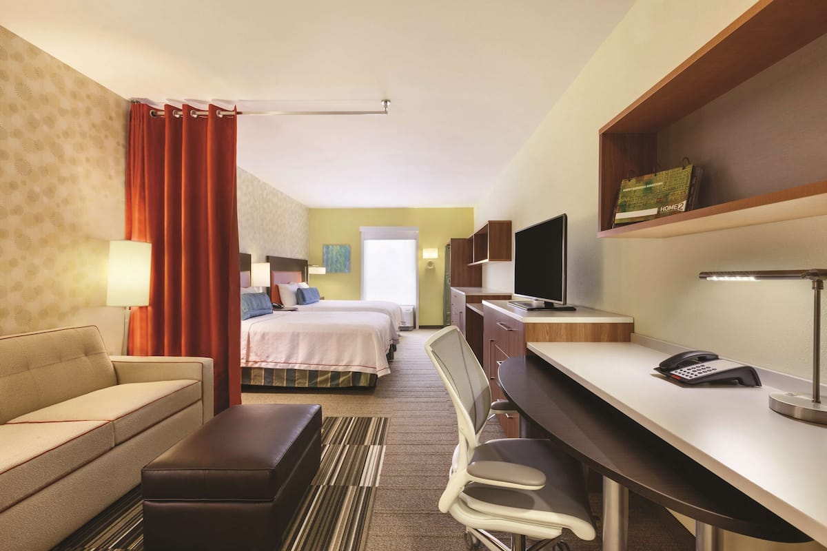 Une chambre d’hôtel équipée d’un lit, d’un bureau, d’une chaise, d’un canapé, d’une télévision et d’une lampe.