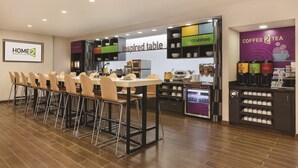 A hotel dining area with a long table and chairs, a coffee and tea station, and a sign for "Inspired table."