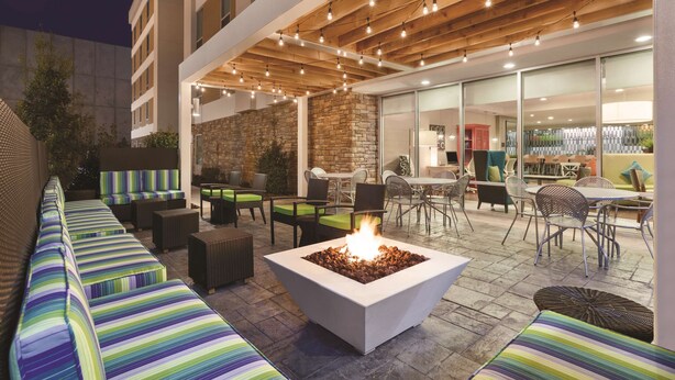 An outdoor patio area with a fire pit, seating, and dining tables.