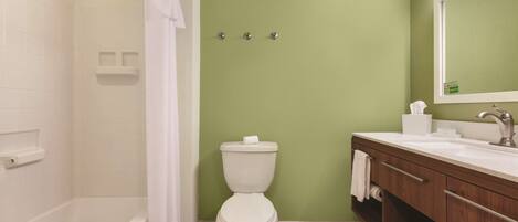 A bathroom with a bathtub, toilet, and vanity with a mirror.