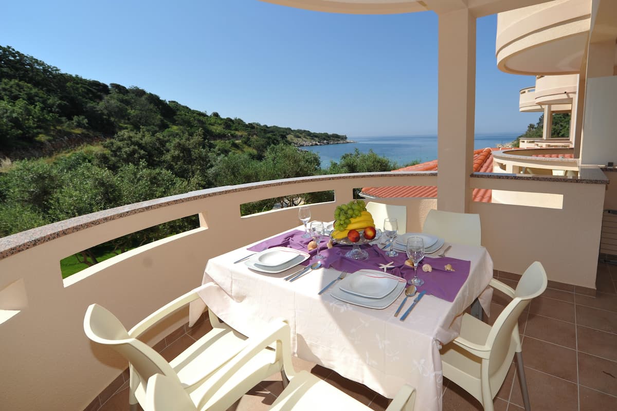 A table set for two with a view of the sea and hills.