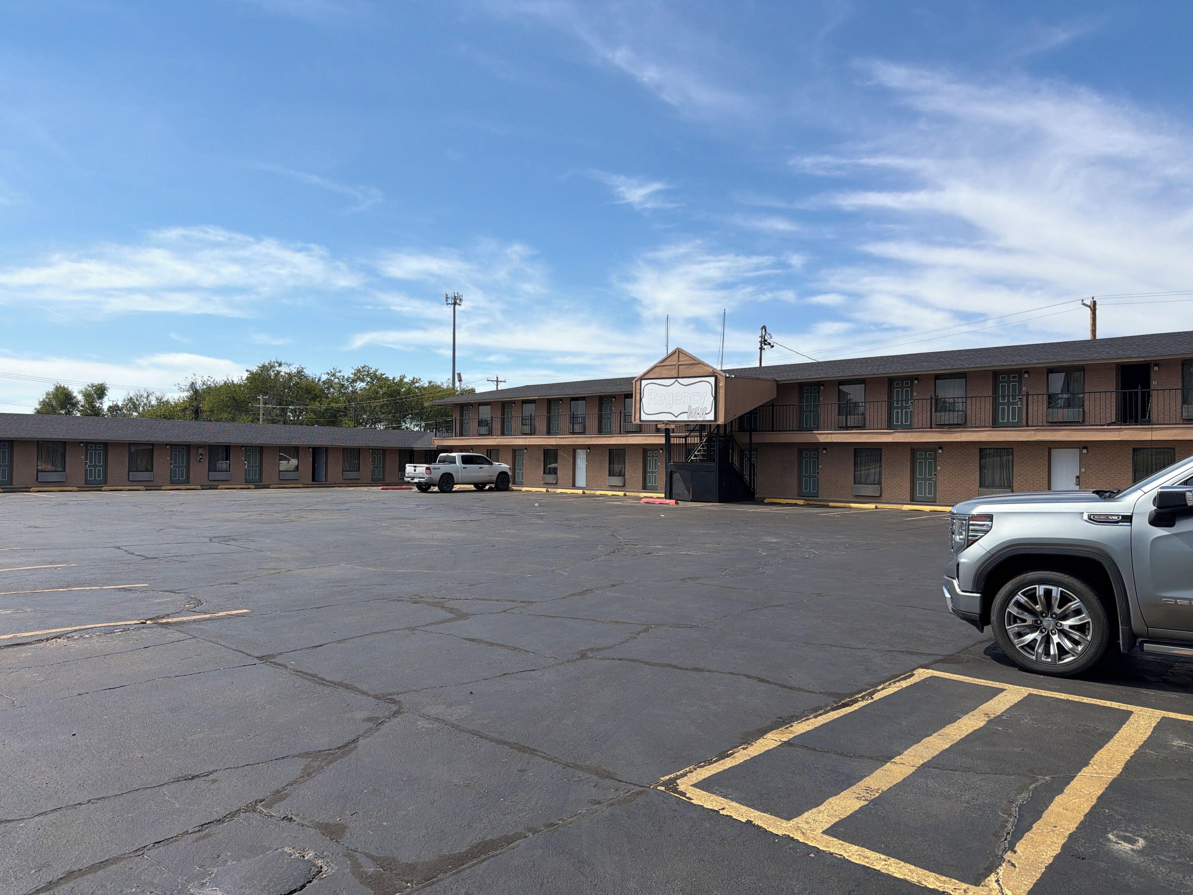 A motel with a parking lot, a white pickup truck, and a silver SUV parked.