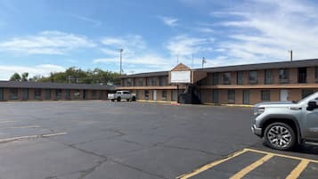 A motel with a parking lot, a white pickup truck, and a silver SUV parked.