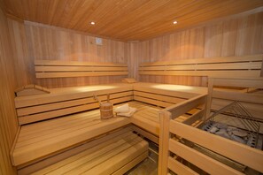 Relax in a serene sauna room with wooden benches and amenities at hand.