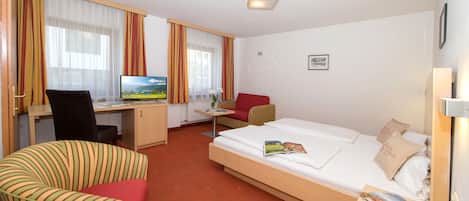 A hotel room with a bed, a desk, a chair, and a TV.