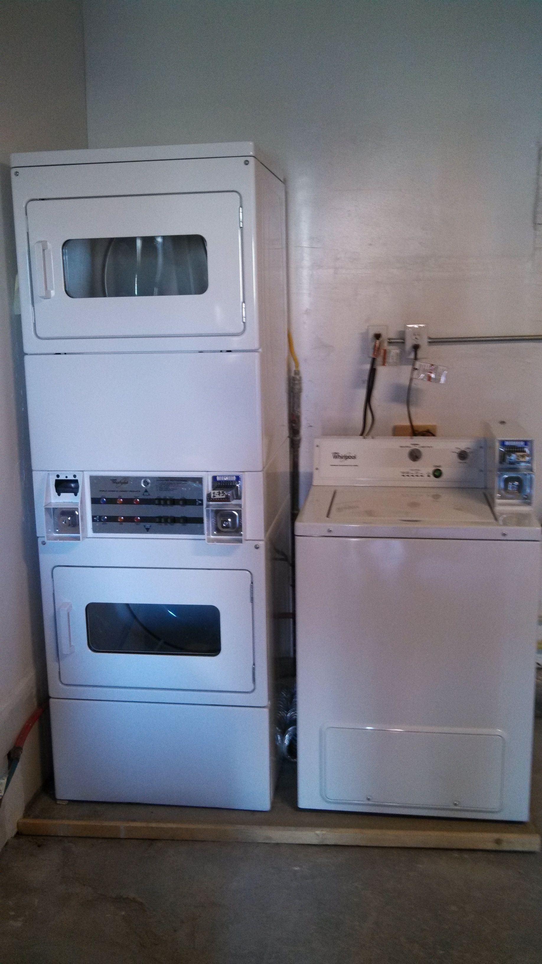 A laundry room with stacked washing machines and a dryer.