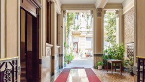 A hallway with a red carpet, columns, and potted plants. - Milan Retreats - Central Station (Milan)