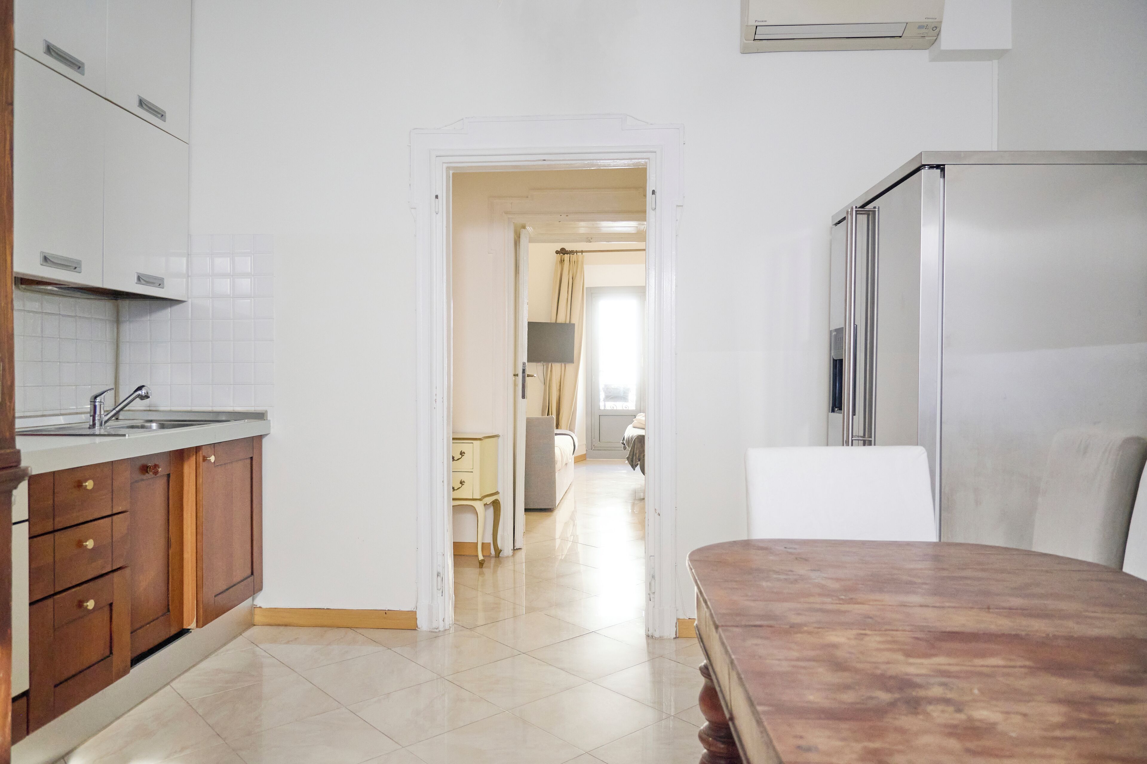 A kitchen with white cabinets, a stainless steel refrigerator, and a wooden table.