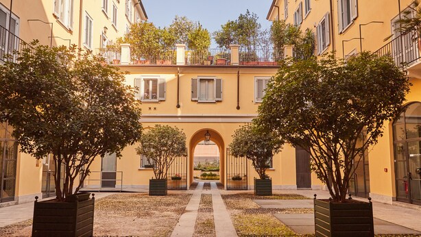 A courtyard with a central pathway flanked by trees and buildings with balconies. - Milan Retreats - Central Station (Milan)