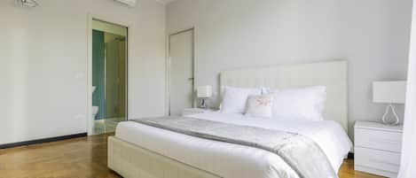 A modern bedroom with a large bed, a bedside table, a nightstand, and a walk-in closet.