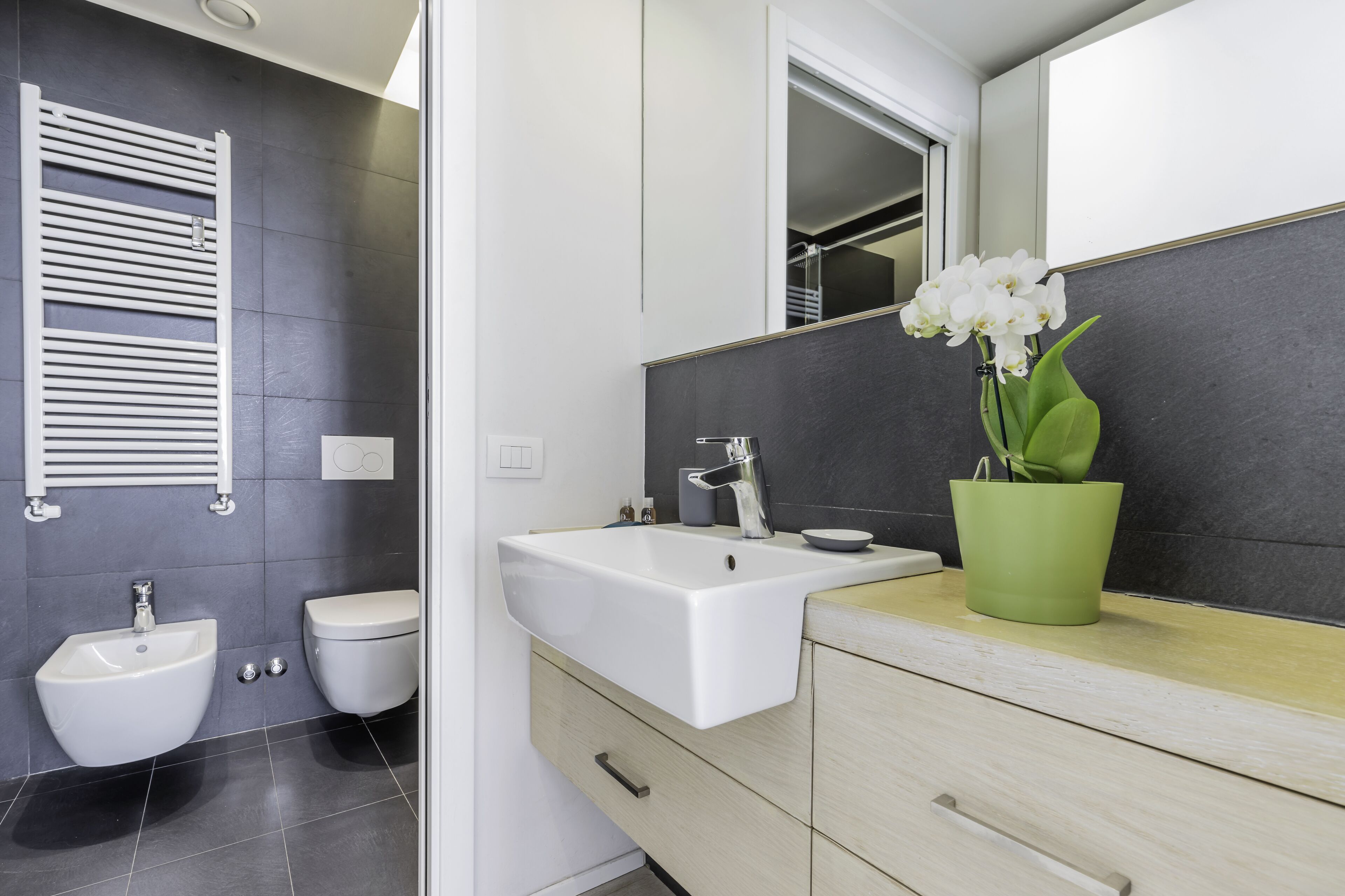 Un baño moderno con un lavamanos blanco, un inodoro y un perchero para toallas.