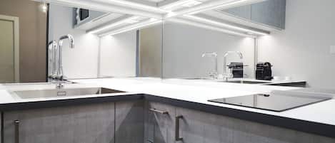 A modern kitchen with two sinks, a coffee machine, and a large mirror.