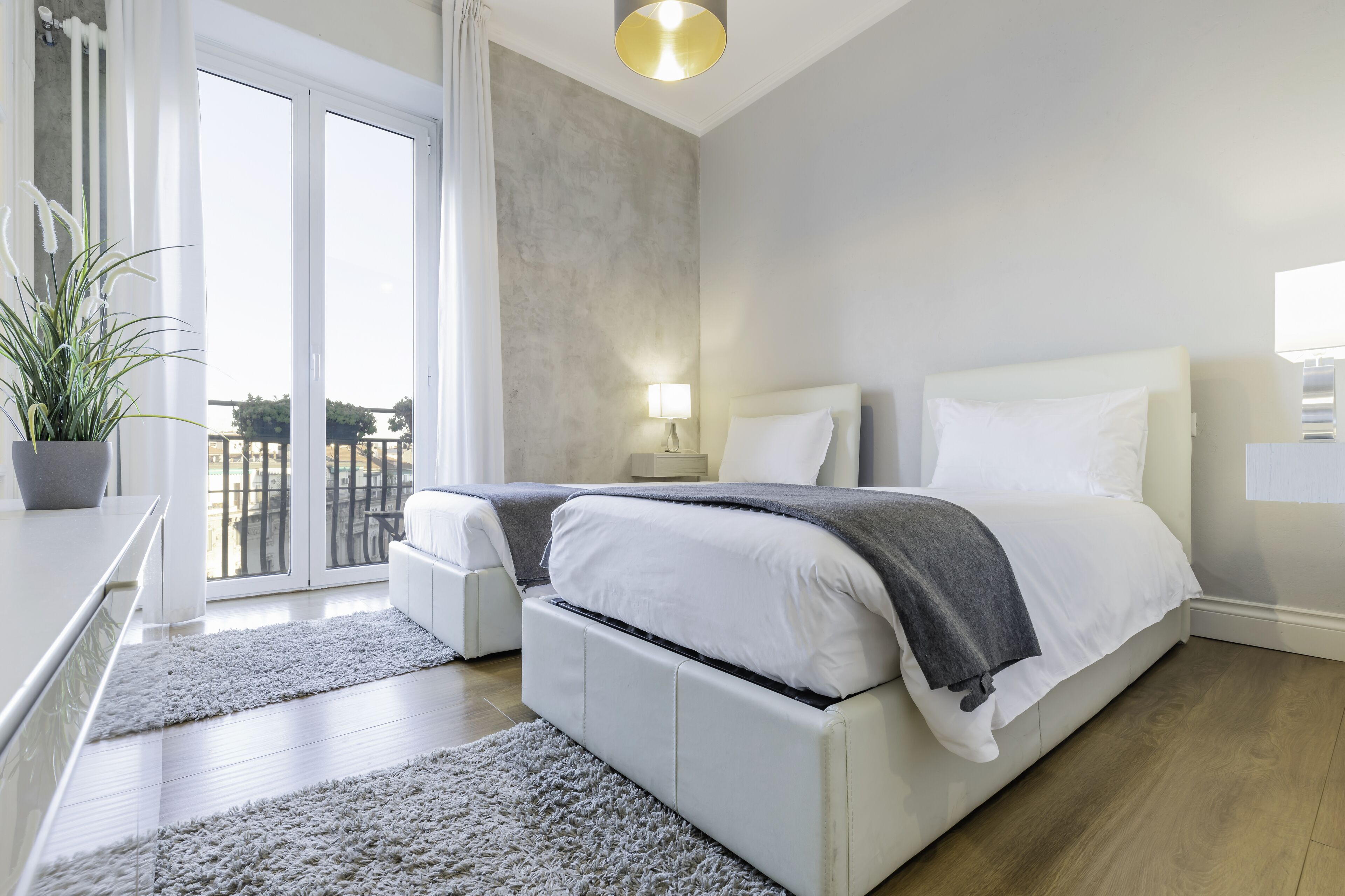 Une chambre à coucher moderne avec un grand lit, une table de chevet, une lampe et une plante en pot.