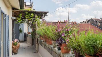 A balcony with potted plants and a pergola.