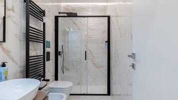 Et moderne badeværelse med en stor hvid vask, toilet og et bruseområde med glasvægge.