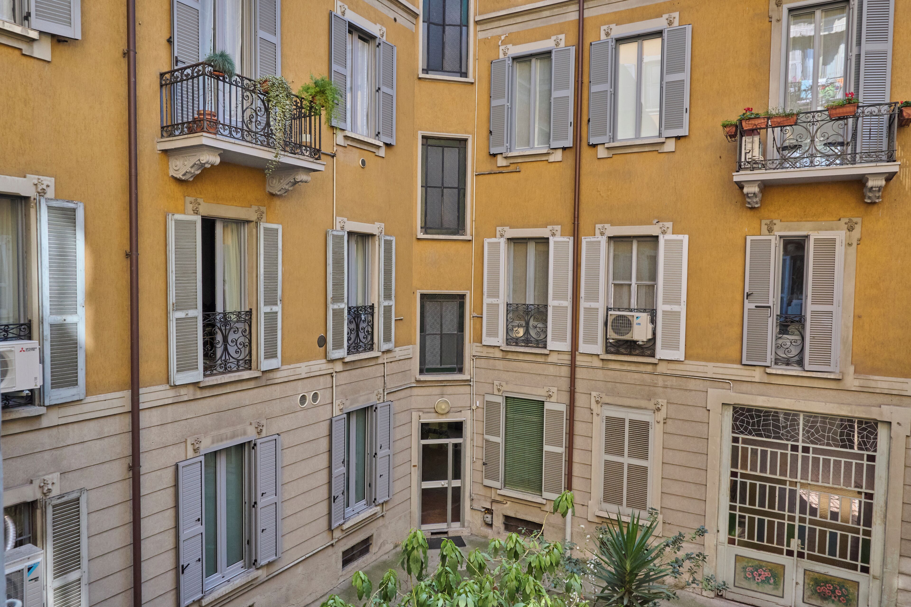 A multi-story building with balconies, shutters, and a central courtyard.