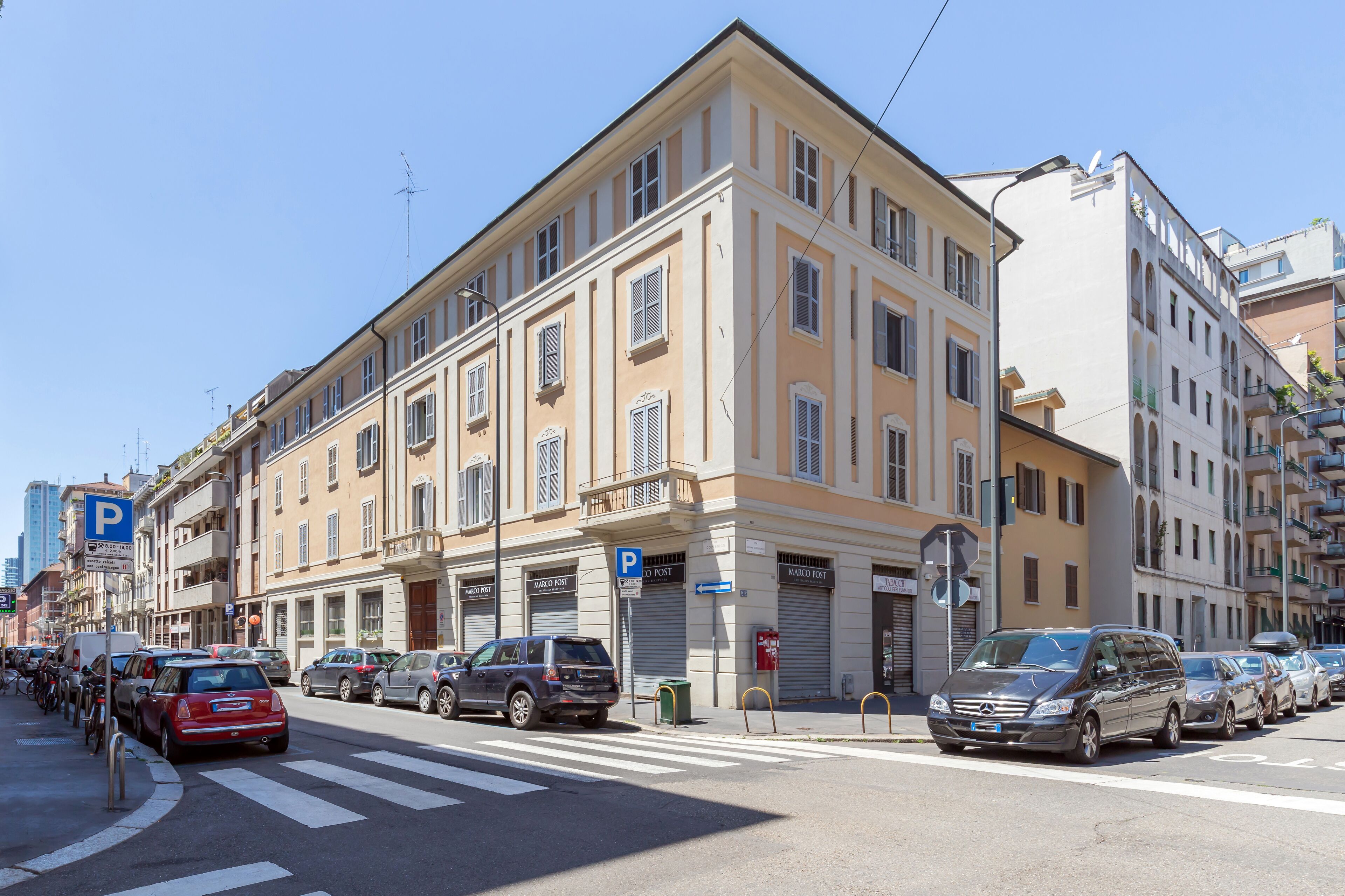 Un immeuble à plusieurs étages, avec des commerces au rez-de-chaussée et un espace de stationnement.